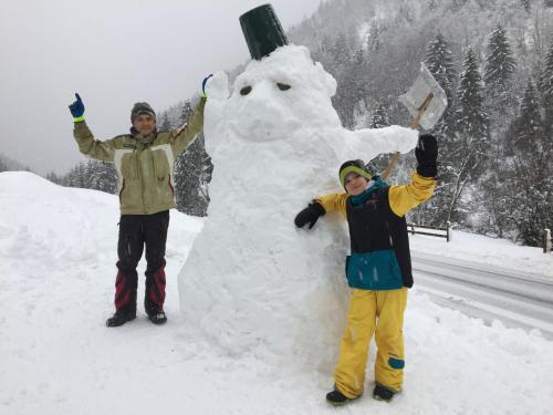 a man and a boy standing next to a snowman at Alpenapart Walch in Jerzens