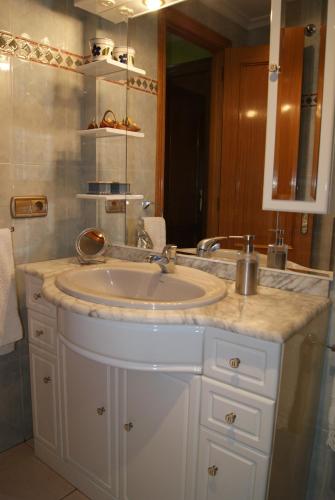 La salle de bains est pourvue d'un lavabo et d'un miroir. dans l'établissement Apartamento El Caminito, à Ponferrada