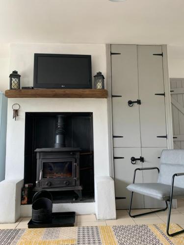 a living room with a fireplace with a television above it at Windmill cottage in Donegal