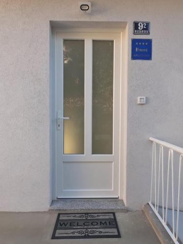 a white door on a white building with a sign at Apartment More 13 in Rabac