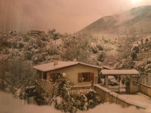 a house covered in snow next to a mountain at Il Bosco Guest House Subiaco in Subiaco