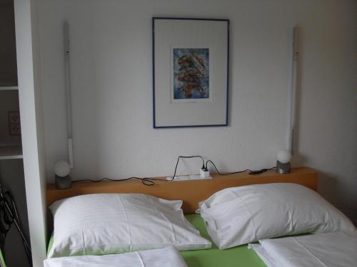 a bed with two white pillows and a picture on the wall at Haus Edith Privathaus mit Gästezimmern in Bregenz