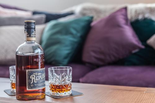 a bottle of rye whiskey and two glasses on a table at Chalets Royal, Tatranská Lomnica in Tatranská Lomnica