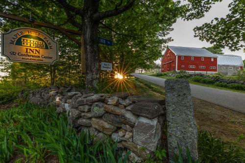 a sign and a stone wall in front of a barn at Maple Hill Farm Inn in Augusta