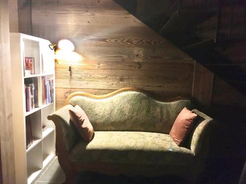 a green couch in a room with a book shelf at A Côté in Oron-la-ville