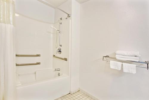 a white bathroom with a shower and white towels at Travelodge Suites by Wyndham MacClenny I-10 in Macclenny