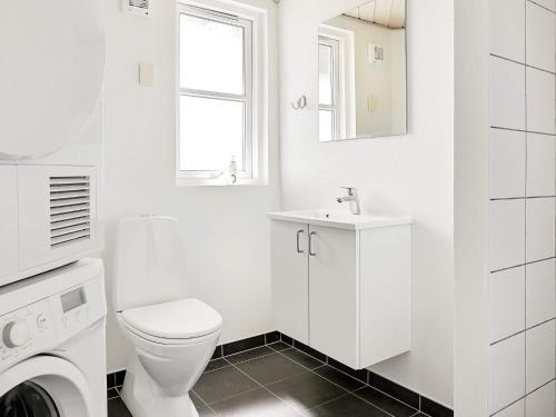 Baño blanco con aseo y lavamanos en Nine-Bedroom Holiday home in Idestrup 2, en Bøtø By