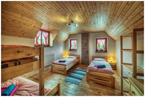 a bedroom with two bunk beds and a wooden ceiling at Chata Margitka in Dúbrava