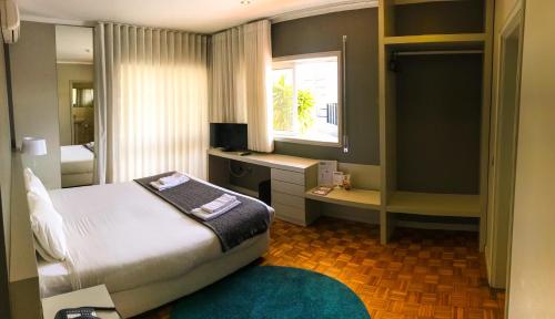 a bedroom with a bed and a desk and a window at Hotel do Paço in Guimarães