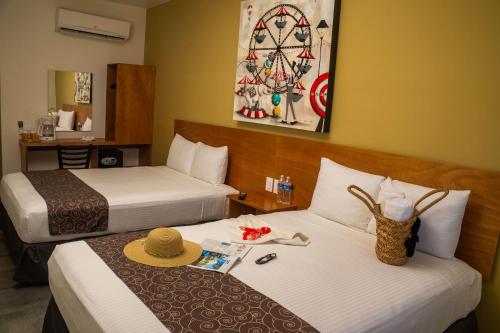 Habitación de hotel con 2 camas con sombreros. en AM Hotel y Plaza, en Santa Cruz Huatulco