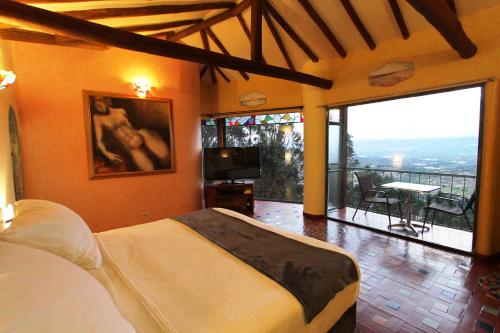 a bedroom with a bed and a balcony with a view at Suites Arcoiris in Villa de Leyva