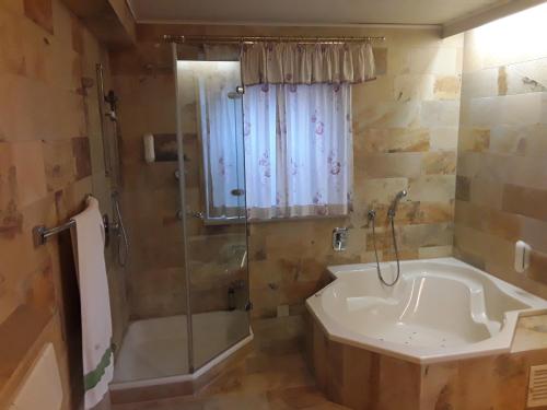 a bathroom with a tub and a shower with a shower curtain at Hotel Feiler in Muggendorf