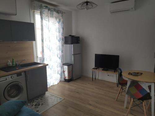 a living room with a washing machine and a table at Agréable T2 au calme proche gare in Perpignan