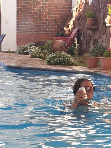 a woman in a swimming pool holding a drink at Hotel Mitru in Tupiza