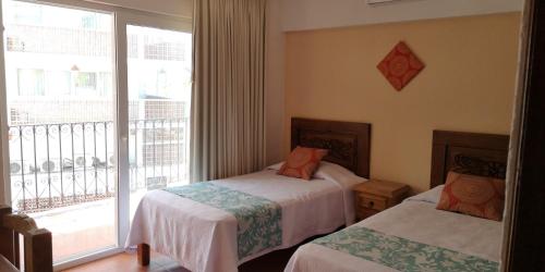 a bedroom with two beds and a window with a balcony at Estrella de Mar in Puerto Vallarta