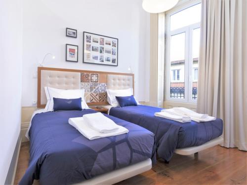 um quarto com 2 camas com lençóis azuis e uma janela em Vanzeleres 285 no Porto