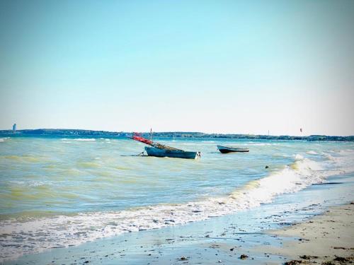 two boats sitting in the water on the beach at FeWo SANDKORN - Familien- Hunde - strandnah - große Loggia - Sauna & Wellness in Sierksdorf
