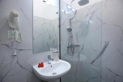 a white bathroom with a sink and a shower at Apartments Avra in Lefkada