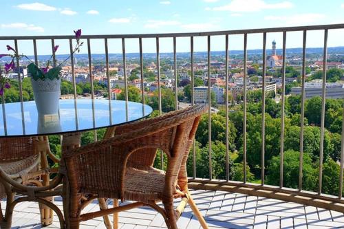 a glass table and chairs on a balcony with a view at SUITE-XXI City View Hotelturm Augsburg in Augsburg