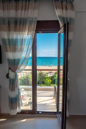 a room with a door open to a view of the ocean at Dimi Seafront Apartment by Rentals Pro Services - Nea Moudania in Nea Moudania