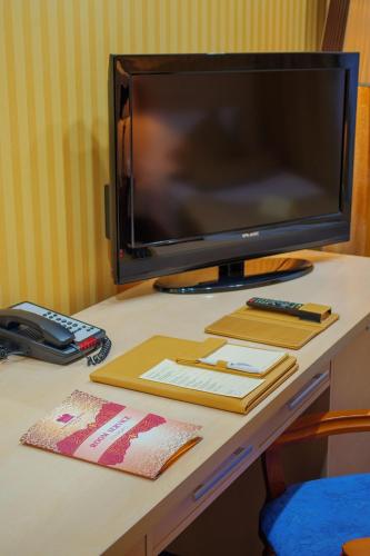 a desk with a television and a keyboard and books at King Hotel Astana in Astana