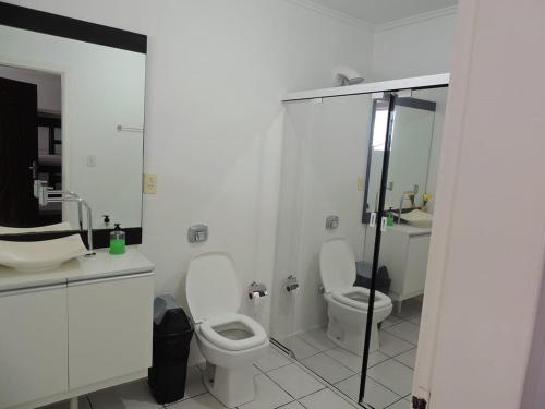 Baño blanco con 2 aseos y ducha en Positive Hostel, en Balneário Camboriú