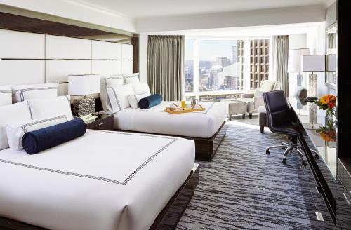 a hotel room with two beds and a desk at Pan Pacific Vancouver in Vancouver