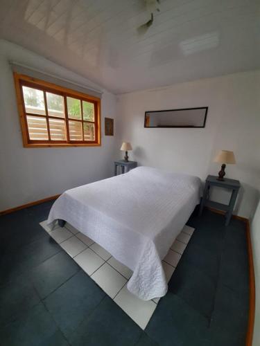 a bedroom with a white bed with two tables and a window at Marittimo Cabañas in José Ignacio