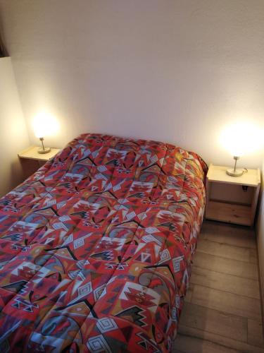 - un lit avec une couette colorée dans une chambre dans l'établissement Font-romeu via odeillo jolie Appartement 6 personnes plein sud, à Font-Romeu-Odeillo-Via