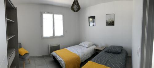 1 dormitorio con 2 camas y ventana en Villa les agrumes, en Narbona