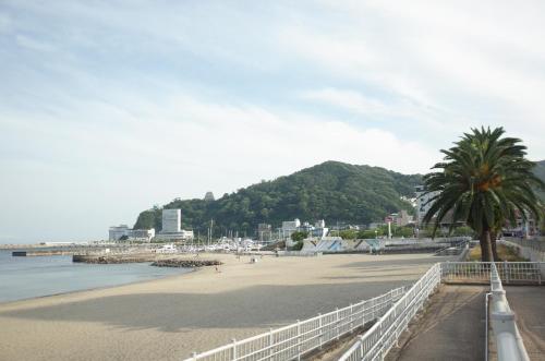 a beach with a white fence and a palm tree at bnb+Atami Resort in Atami