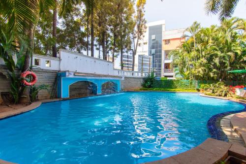 a large blue swimming pool with trees and buildings at Halcyon Hotel Residences - Bangalore in Bangalore