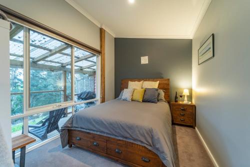 a bedroom with a bed and a large window at Platypus Waters B&B in Smithton
