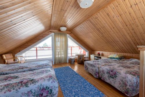 a attic bedroom with two beds and a large window at Wild Stay - Ounasrannan majat, Tepasto in Tepasto