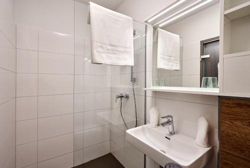W białej łazience znajduje się umywalka i lustro. w obiekcie Workers Home w mieście Zipf