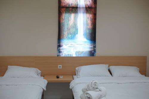 two beds in a room with a painting on the wall at Gold Line Guest House in Pontianak