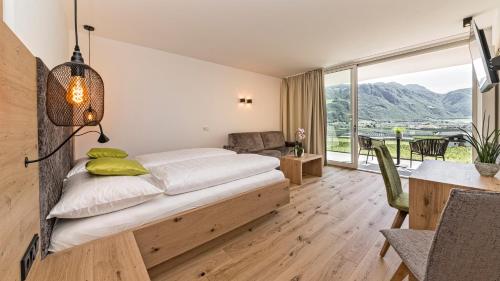 a bedroom with a bed and a table with a chair at Hotel Garni Sonngart in Andrian