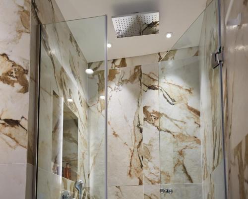 a bathroom with a shower with marble walls at City Lion by Semavi in Heraklio Town