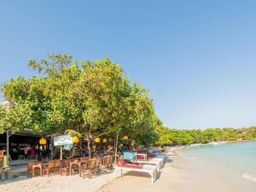 a beach with tables and chairs and the water at Tom Pizza Resort in Ko Samed