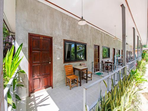 a patio with tables and chairs and a wooden door at Tom Pizza Resort in Ko Samed