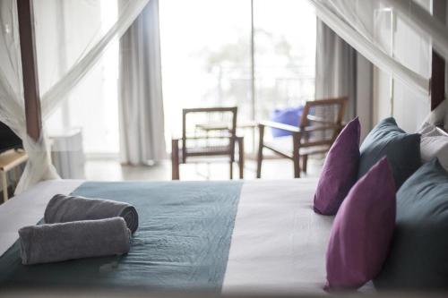 a bed with purple and blue pillows in a room at Seals Harbor Hotel in Weligama