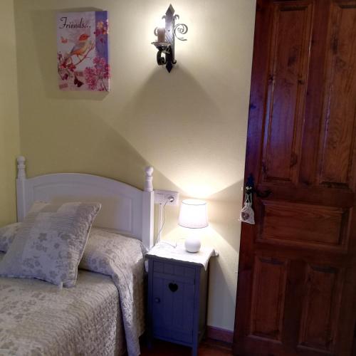 a bedroom with a bed and a lamp next to a door at LA CASUCA Y LA CABAÑA in Ojedo