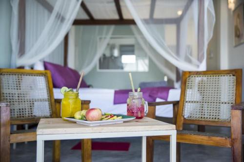 a table with a plate of fruit and drinks on it at Seals Harbor Hotel in Weligama