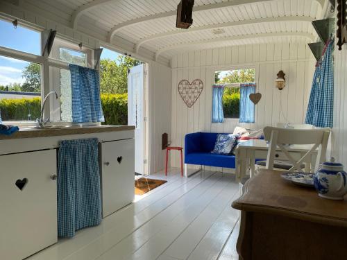 Il comprend une cuisine et un salon avec une table. dans l'établissement Little blue house (on the campsite), à Oostvoorne