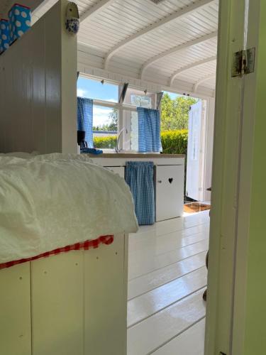 cocina con armarios blancos y suelo de madera en Little blue house (on the campsite), en Oostvoorne