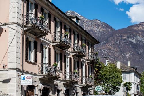 ein Gebäude mit Balkon auf einer Straße vor den Bergen in der Unterkunft Palazzo Pellanda in Domodossola