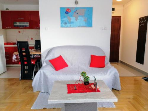 sypialnia z łóżkiem z czerwonymi poduszkami i stołem w obiekcie Good Host w mieście Banja Luka