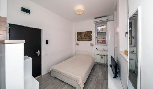 a small white bedroom with a bed and a window at New Charming Studio in Bucharest