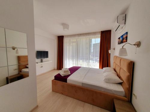 a bedroom with a large bed and a window at MIANELLY Apartments Mamaia Nord in Mamaia Nord