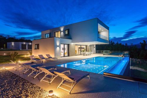 a villa with a swimming pool at night at Villa SUNRISE DREAM in Grubine